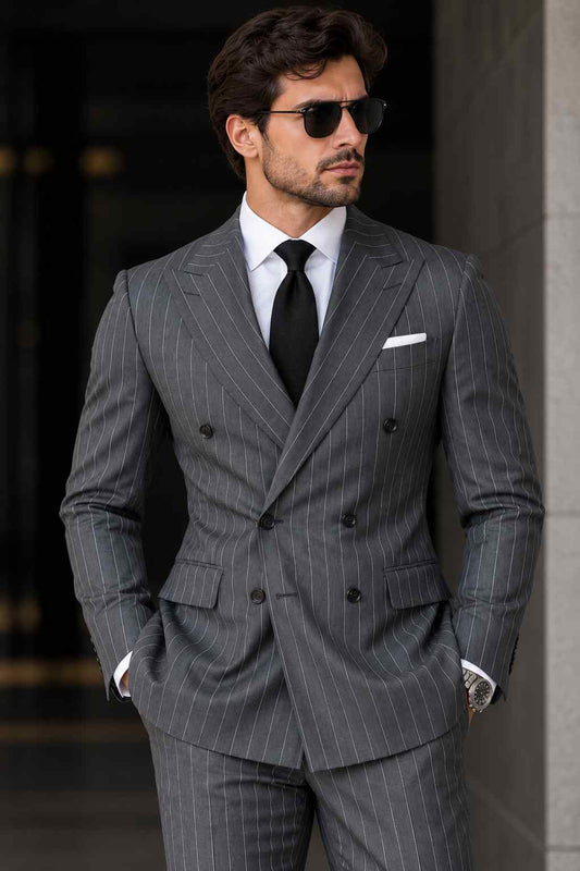 Man wearing a charcoal grey pinstripe double-breasted suit with wide peak lapels, white shirt, black tie, and white pocket square.