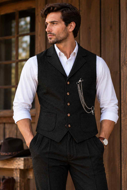 Man wearing a black tweed wool waistcoat with brown buttons, notched lapels, front pockets, and a decorative pocket chain over a white dress shirt.