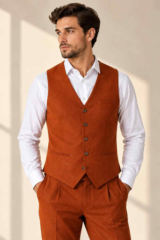Man wearing a rust terracotta waistcoat with dark buttons, a V-neck design, and front pockets over a crisp white dress shirt.