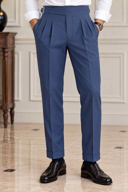 Men's navy blue high-waisted Gurkha trousers featuring double front pleats, adjustable side buckles and turn-up cuffs.