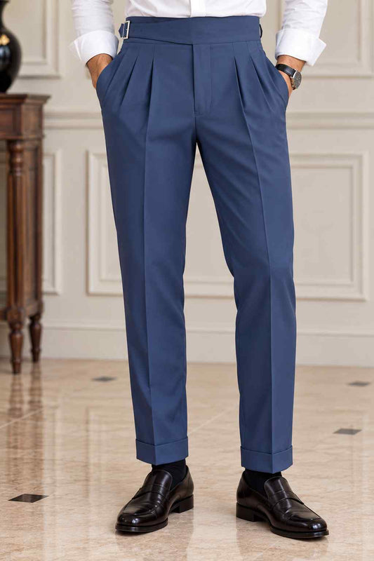 Men's navy blue high-waisted Gurkha trousers featuring double front pleats, adjustable side buckles and turn-up cuffs.