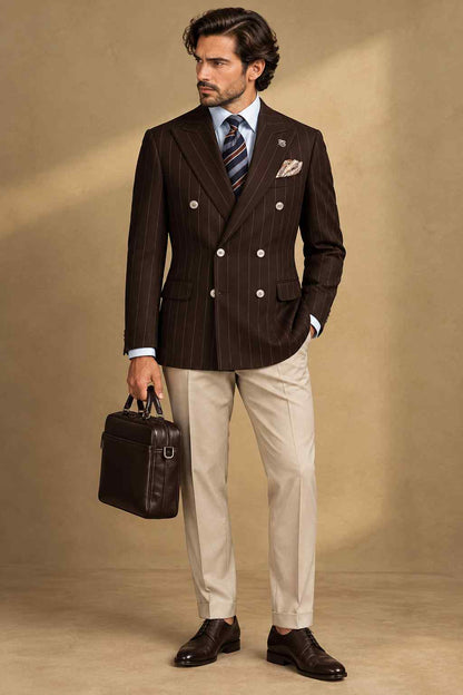 Men's dark brown pinstripe double-breasted blazer with peak lapels, contrasting buttons and a pocket square, styled with a white shirt, striped tie and cream trousers.