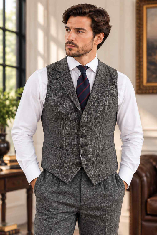 Men’s grey herringbone tweed vest with tailored fit, V-neck, button front, welt pockets, and matching trousers.