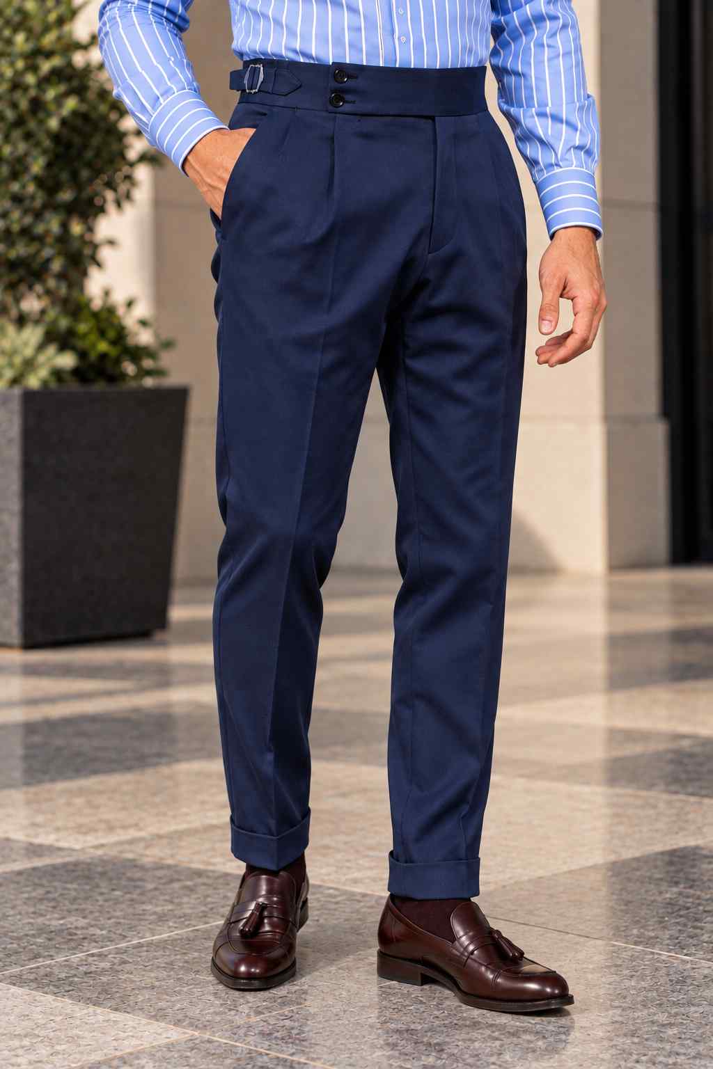Men's navy blue high-waisted Gurkha trousers featuring double front pleats, a double-button waistband, wide legs and turn-up cuffs.