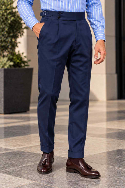 Men's navy blue high-waisted Gurkha trousers featuring double front pleats, a double-button waistband, wide legs and turn-up cuffs.