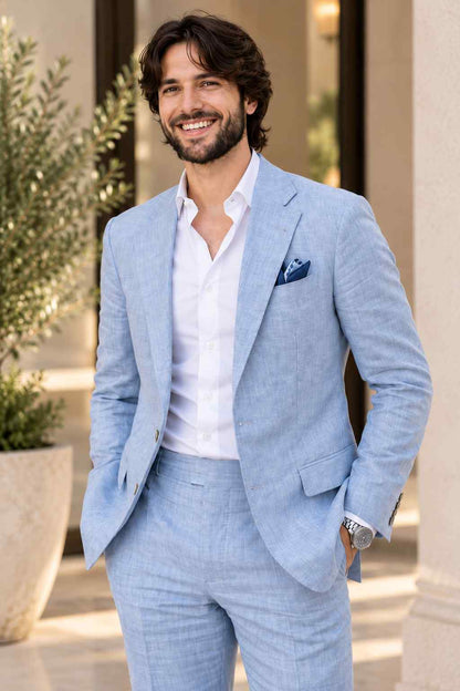 Man wearing a sky blue linen 2-piece suit with a matching blazer and trousers, white shirt, and navy pocket square.