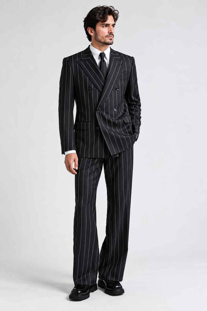 Full-length view of a man wearing a black pinstripe double-breasted suit with white stripes, wide peak lapels, a white shirt, and black tie.