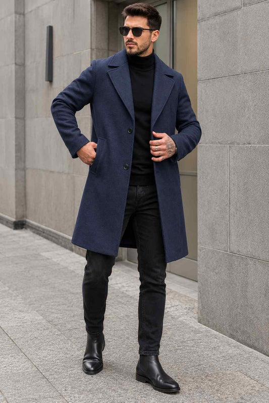 Man wearing a navy blue tweed wool long coat with black turtleneck, black jeans, and sunglasses.